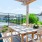 a table and chairs on a deck in front of a tennis court