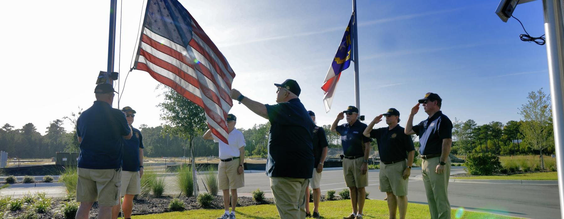 a group of people standing on a grass field with flags